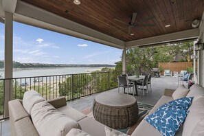 A covered patio with a view of a lake, outdoor furniture, and a dining area. - Lakefront Home with Captained Part Boat, Private Dock, Beach, Game-room (Lago Vista)