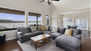 A spacious living room with a large sectional sofa, a wooden coffee table, and a ceiling fan.