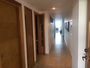 A hallway with wooden doors, a tiled floor, and a view into a dining area.