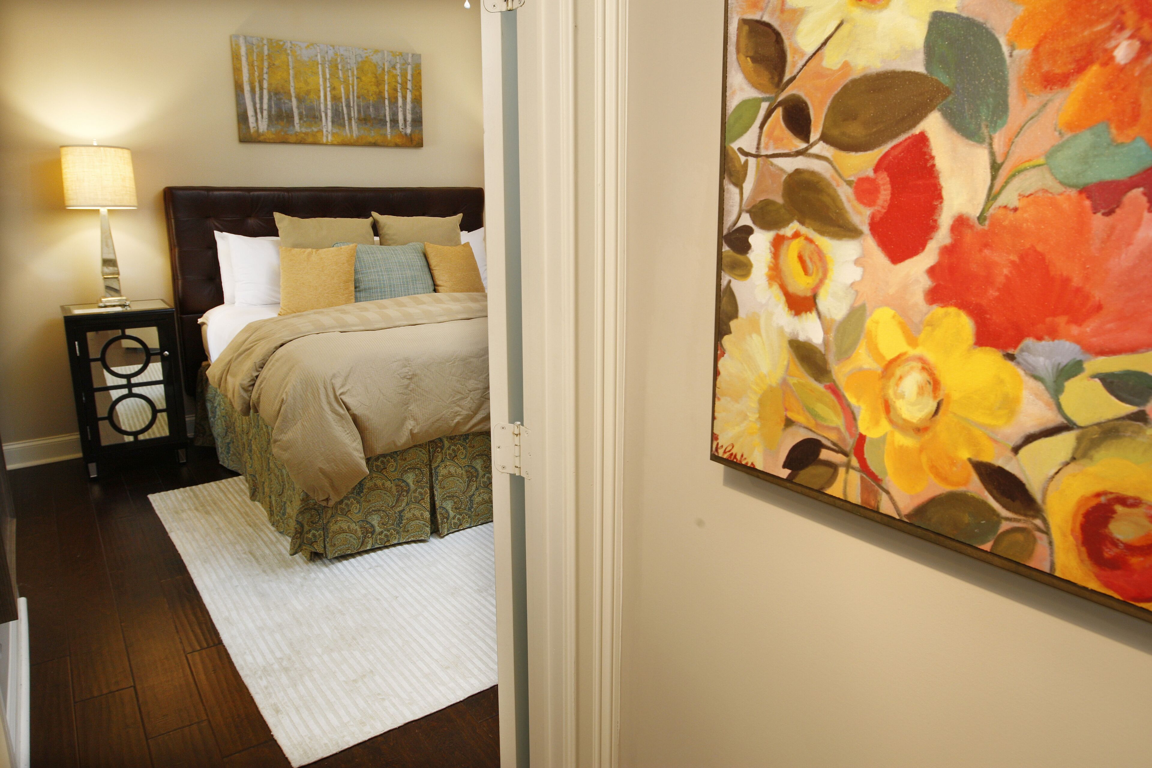 A bedroom with a bed, nightstand, and a painting on the wall.