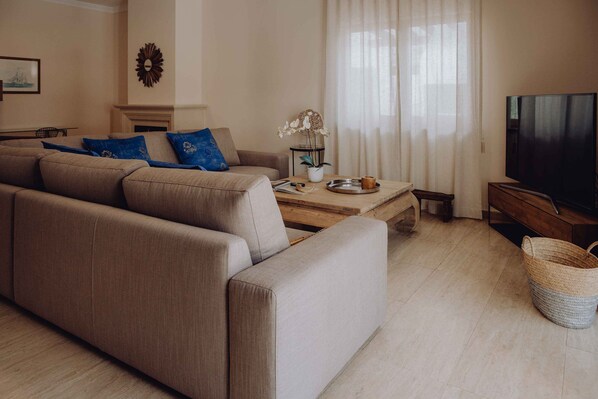 A living room with a beige sofa, a coffee table, a TV, and a fireplace.