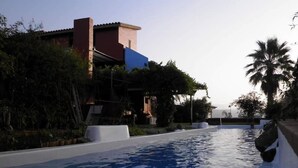 Une piscine offrant une vue dégagée sur les environs, notamment sur un bâtiment à la façade rouge et bleue et sur une végétation luxuriante.
