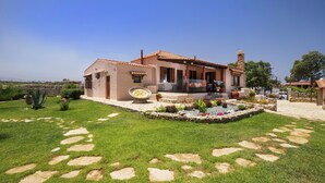 Una casa con patio, un jardín con piedras y un cielo despejado.