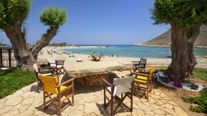 Un patio de piedra con una mesa redonda y sillas con vista a la playa.