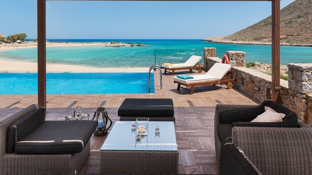 Una pérgola de madera con vista a una playa y un mar azul cristalino.