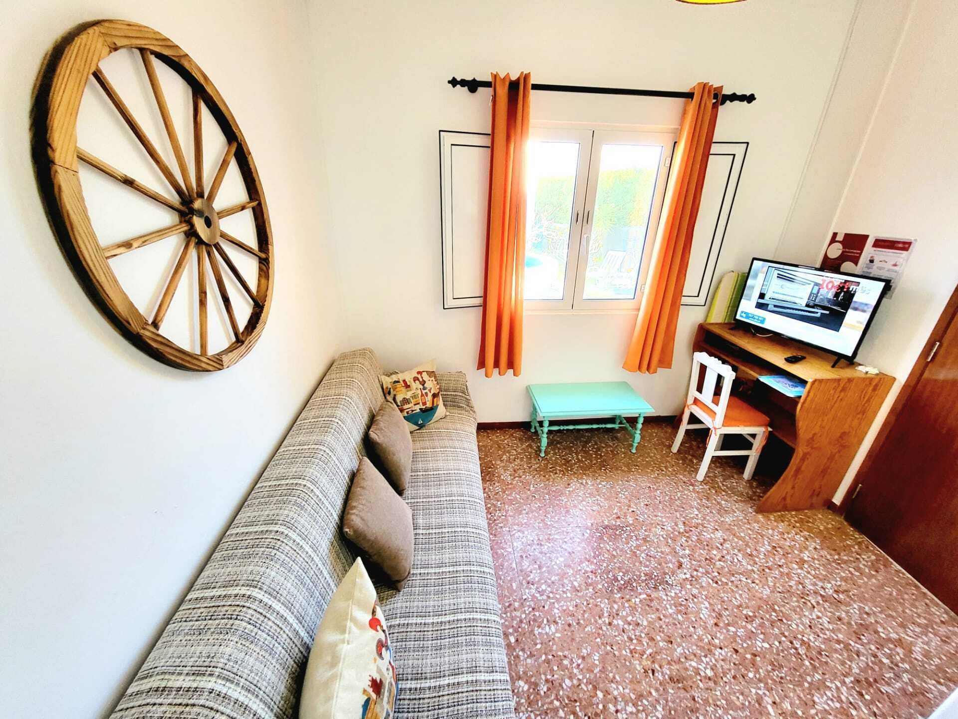 Un salon confortable avec un canapé, une roue en bois, une petite table, une chaise et un téléviseur.