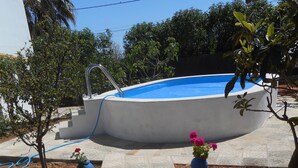 A swimming pool with a tiled deck, surrounded by potted plants and trees. - Typical Algarve House - Fuzeta, Arrroteia "Casas carpinteiro" (Tavira)