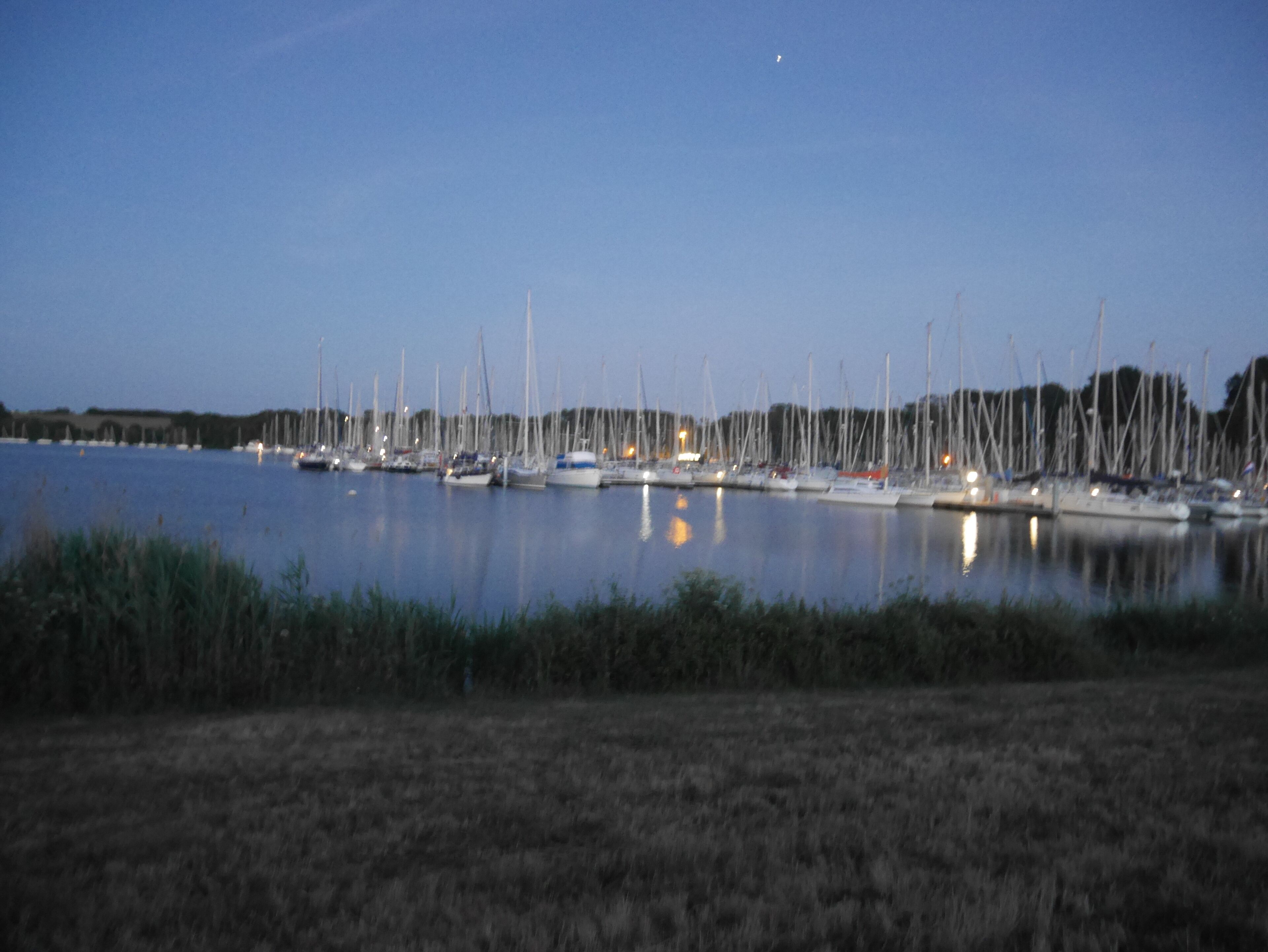 Un port de plaisance où de nombreux bateaux sont amarrés dans des eaux calmes, au crépuscule.