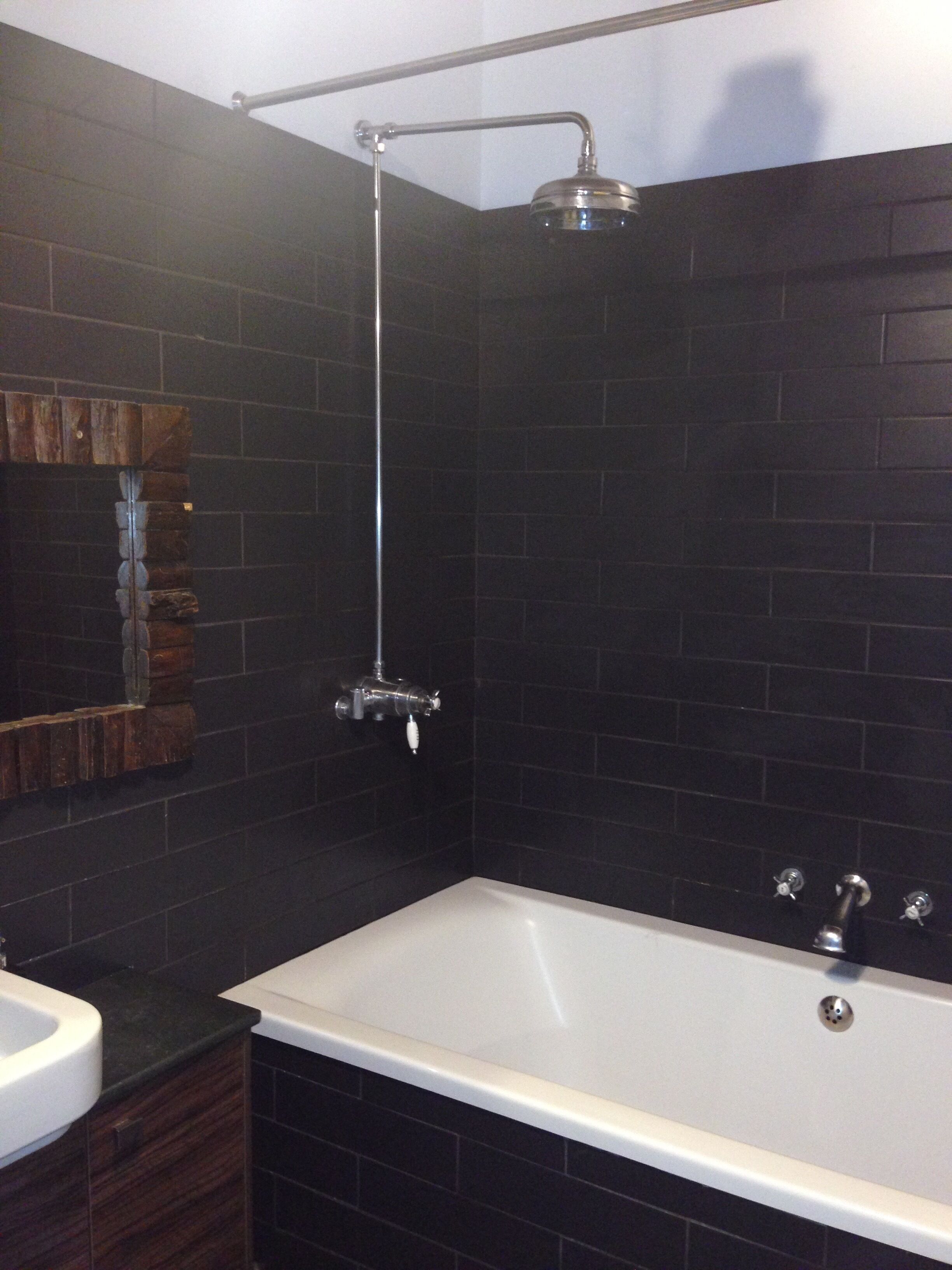 A modern bathroom with a bathtub, a showerhead, and a mirror.