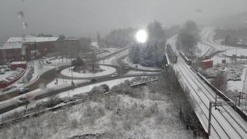 Ett snötäckt stadsmiljö med en rondell, ett järnvägsspår och en byggnad med ett rött tak.