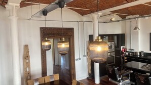 Una cocina moderna con electrodomésticos de acero inoxidable, una barra con taburetes e iluminación colgante.