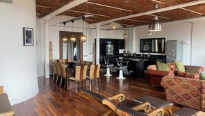 Amplia sala de estar con una mesa de comedor, sofás y una cocina al fondo.