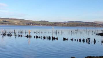 A calm lake with a rocky shoreline and distant hills.