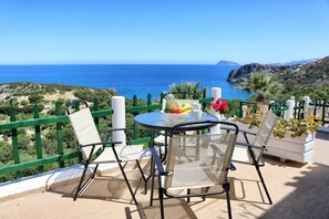 Un balcon avec une table et des chaises donnant sur une vue sur la côte.