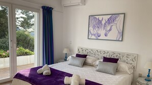 Une chambre à coucher avec un lit, des oreillers, une tête de lit, une fenêtre avec des rideaux, un tableau et une table de chevet.
