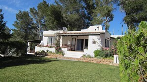Une maison blanche dotée d’un patio, entourée de verdure et d’arbres.