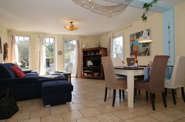 A living room with a sofa, ottoman, and a dining area with chairs and a table. - Whirlpool, Fireplace,SAUNA,SKY TV, Terrace&Grill,Fireplace,Rain shower (Mecklenburg / Vorpommern)