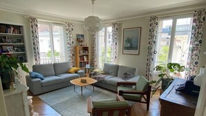 A spacious living room with a sofa, armchairs, a coffee table, and a bookshelf. - Large Family Apartment in Paris (Paris)