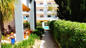 Un camí flanquejat per plantes en testos i un edifici amb balcons.