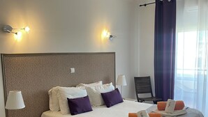Habitació d'hotel amb un llit gran, dues taules de nit, una làmpada i una cadira.