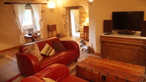 A cozy living room with a red sofa, a wooden cabinet, and a television. - House for 10 people, close to the Gulf of Morbihan, Carnac, Trinité-sur-Mer (Brech)