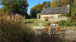 A stone house with a sloped roof and multiple windows, surrounded by a garden with a stone bench and a white fence. - House for 10 people, close to the Gulf of Morbihan, Carnac, Trinité-sur-Mer (Brech)