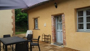 Un patio con una mesa, sillas, una puerta y una ventana.