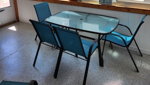 Une pièce avec une table et des chaises, un ventilateur de plafond, une fenêtre avec des rideaux et une vue sur l’extérieur.