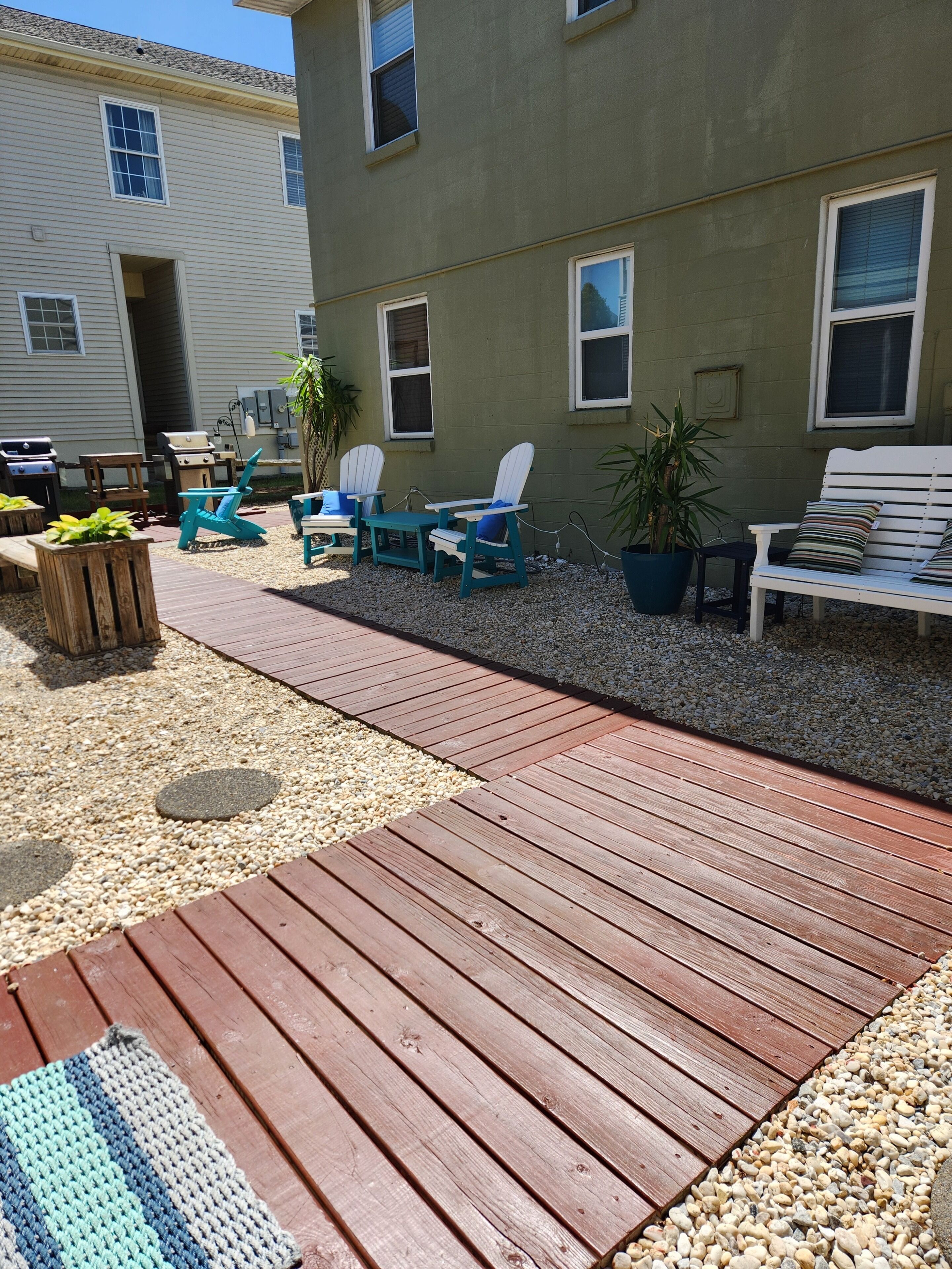 Un patio con mobiliario exterior, una parrilla y una planta en maceta.