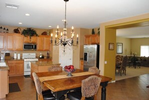 A spacious kitchen with wooden cabinets, a central island, and a chandelier.