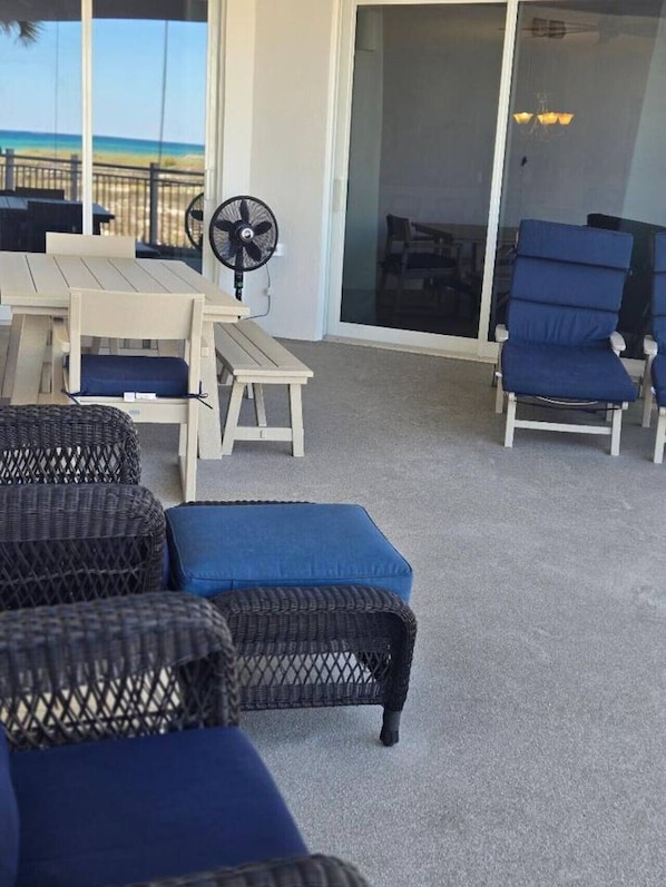 Un espace patio aménagé avec des meubles en osier, une table, des chaises et un ventilateur.