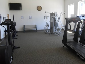 Une salle de sport équipée de tapis de course, de vélos d’appartement et d’un banc de musculation.