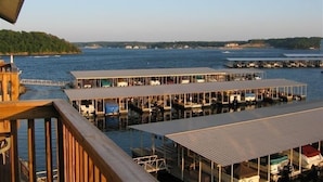 A waterfront property with multiple docked boats, a wooden deck, and a view of the water and distant shoreline.
