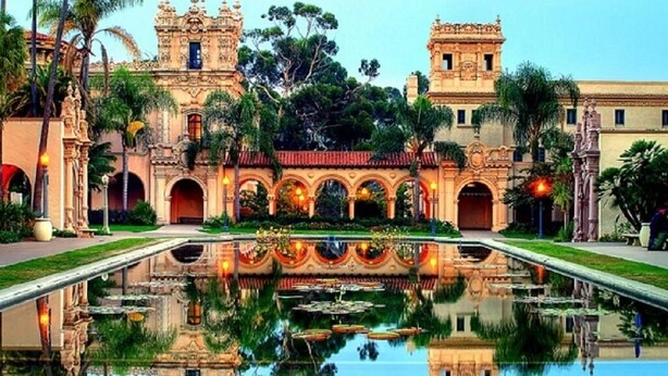 Un edificio histórico con arquitectura ornamentada, un patio central y una fuente de agua reflectante.