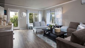 Un salón amplio con un sofá gris, una mesa de centro y un comedor con una mesa de madera oscura.
