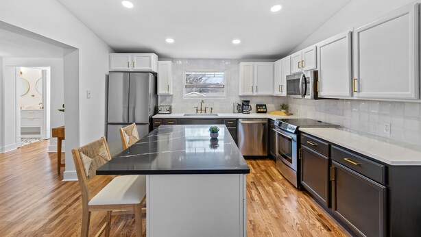 Una cocina moderna con una isla central, electrodomésticos de acero inoxidable y armarios blancos.
