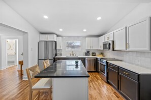 Una cocina moderna con una isla central, electrodomésticos de acero inoxidable y armarios blancos.