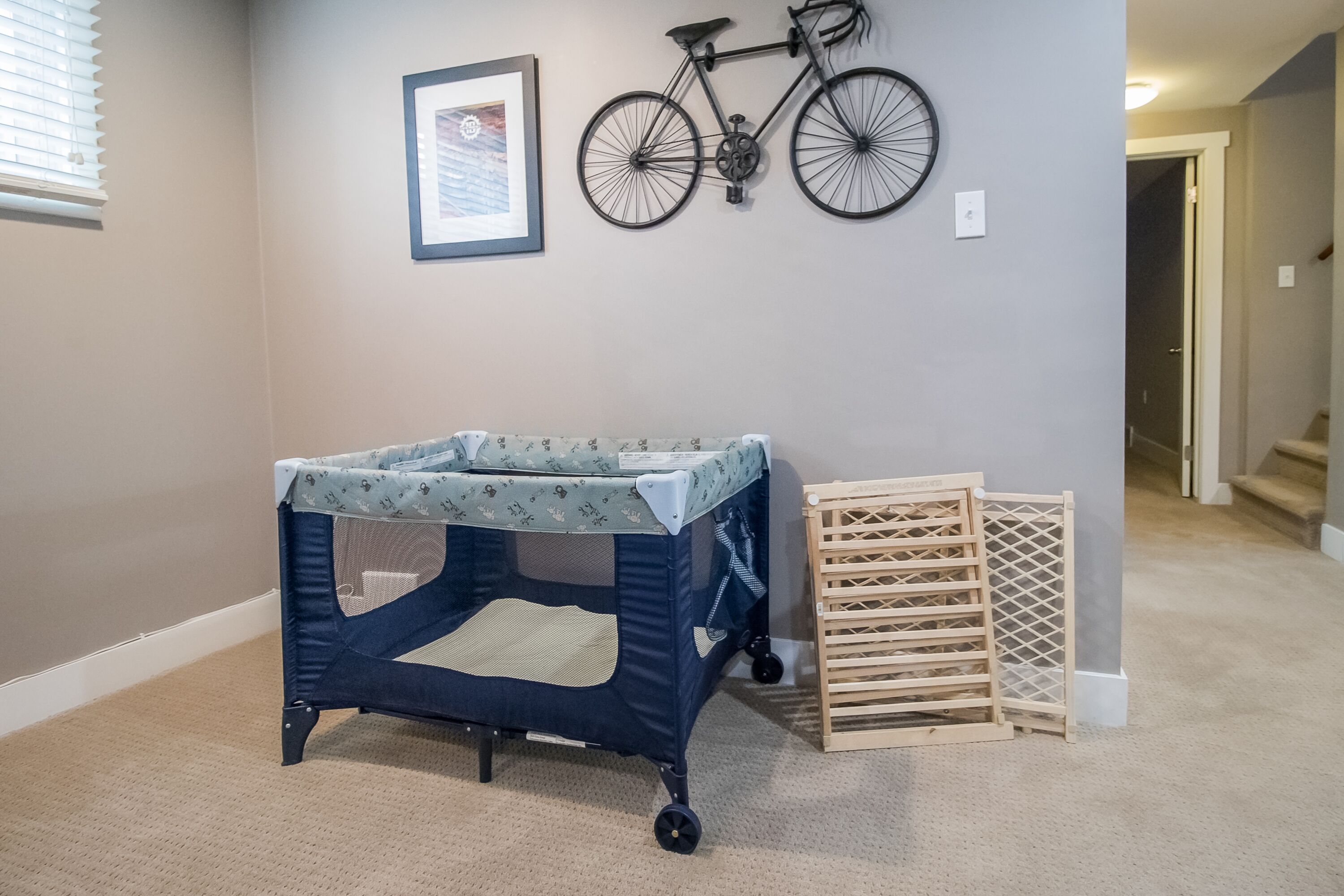 Een kamer met een wiegje, een aan de muur bevestigde fiets en een houten speelrek.