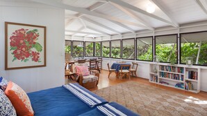A spacious room with a large bed, a dining area, and a bookshelf.