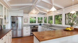 A modern kitchen with white cabinetry, stainless steel appliances, and a wooden island.