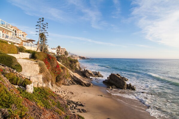 A coastal property with a beach, rocky shoreline, and a view of the ocean.