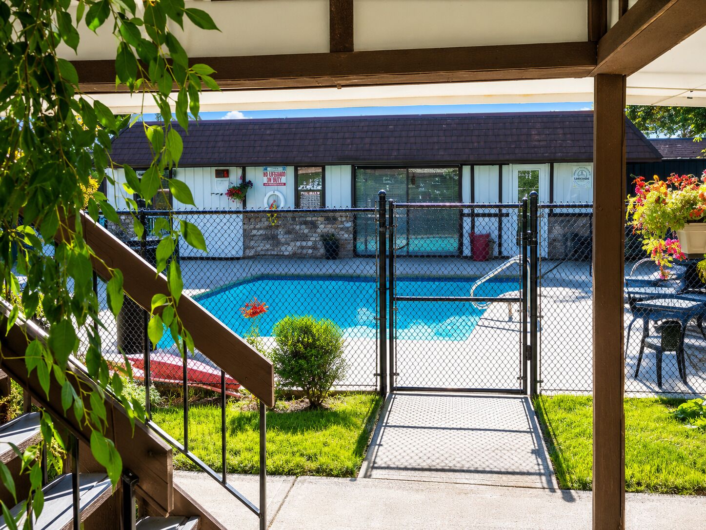 Un espace piscine doté d’une terrasse entourée d’une clôture, d’une petite piscine et d’un bâtiment en arrière-plan.