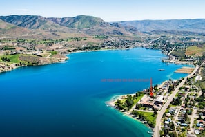 Vista aérea de un pueblo costero con un lago grande, un puerto deportivo y un parque.