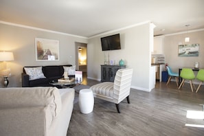 Relax in this stylish living room with a black sofa, armchair, and coffee table, perfect for unwinding with a flat-screen TV and a dining area.