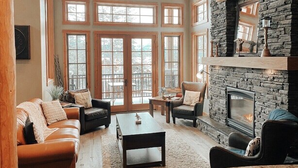 A spacious living room with a stone fireplace, large windows, and a cozy seating area. - Hiking,biking,skiing, family reunion or trip to a national park we have it all!! (Golden)
