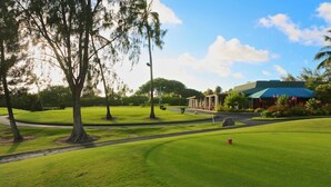 A golf course with a clubhouse, trees, and a clear sky. - Turtle Bay  - Relax In Paradise 570010290183/CCH-0111 (Kahuku)