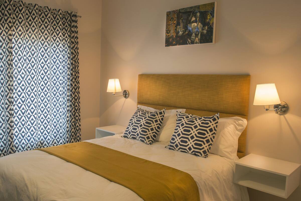 A neatly made bed with patterned pillows, a headboard, and bedside lamps.