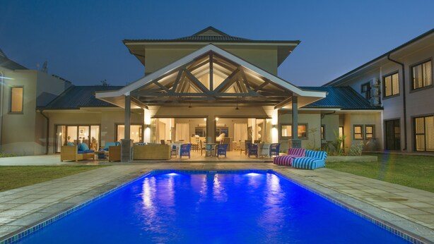 A modern house with a swimming pool, outdoor seating, and a covered patio area. - Greenwood Manor Hotel Ndola (Ndola)