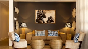 A living room with a sofa, two armchairs, a coffee table, and wall art. - Greenwood Manor Hotel Ndola (Ndola)