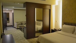 Una habitación de hotel con una cama, un escritorio, una silla, un armario y un espejo.